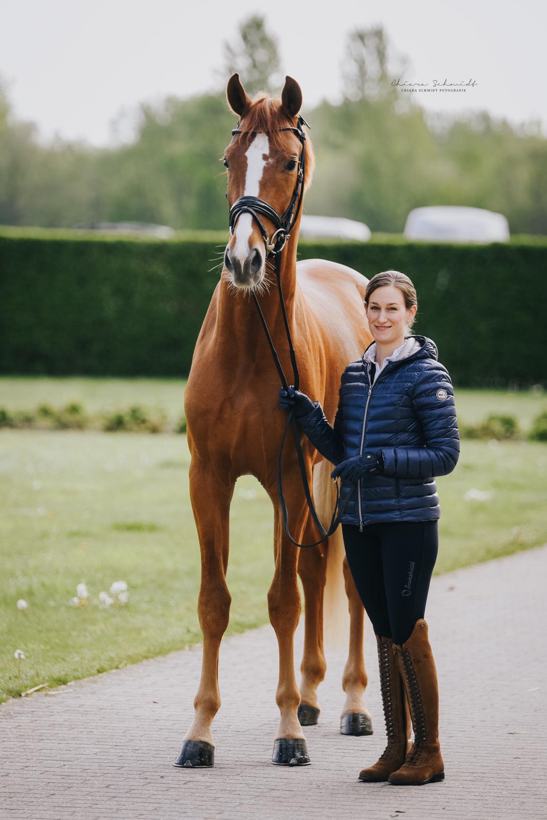 Reiterin steht neben einem Pferd